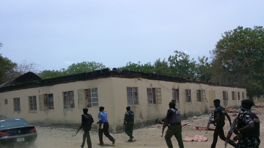 Security walk past the secondary school in Chibok, Nigeria, where gunmen abducted more than 200 students. The government has been criticized for its response to the incident.