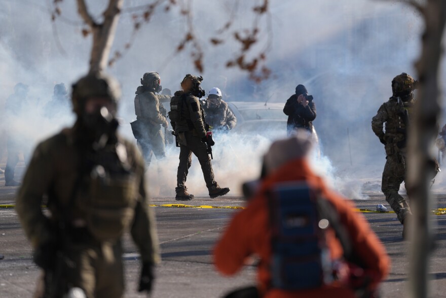 Federal immigration officers deploy tear gas at observers after a shooting Saturday, Jan. 24, 2026, in Minneapolis. (AP Photo/Abbie Parr)
