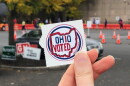 A hand holds an Ohio Voted sticker outside a polling site
