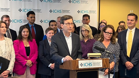 Gov. Bob Ferguson stands at a podium with a crowd behind him. 