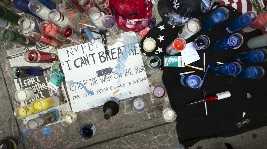 A memorial for Eric Garner rests on the pavement near the site of his death. The poster on the ground quotes Garner; video of the arrest shows him telling police officers he couldn't breathe, shortly before he lost consciousness.