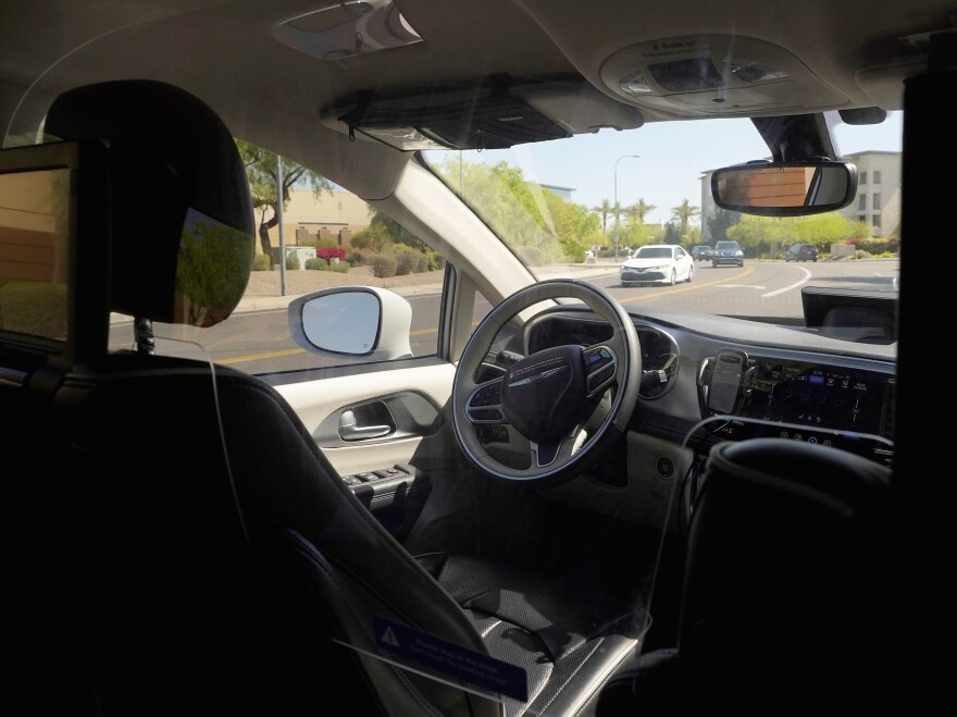 A Waymo minivan moves along a city street during an autonomous vehicle ride on April 7 in Chandler, Ariz. Waymo, a unit of Google parent Alphabet Inc., is one of several companies testing driverless vehicles in the U.S. Auto makers are also developing self-driving technology but it still requires human drivers to take over when required.
