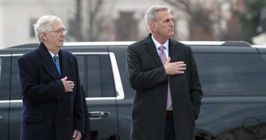 Senate Republican leader Mitch McConnell and House Republican leader Kevin McCarthy watch as a military honor guard carries the flag-draped casket of former Sen. Bob Dole from the U.S. Capitol on Dec. 10, 2021.