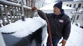 In this photo made Wednesday, Jan. 14, 2014, Paul Dorion, a driver for the Downeast Energy, delivers heating oil to home Portland, Maine.