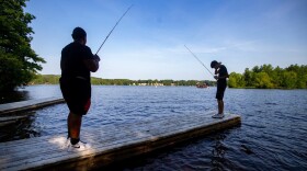 Chaun’cee Smith and Josiah Lopez fish off a dock in Lake Lashaway at Camp Atwater in North Brookfield. (Jesse Costa/WBUR)