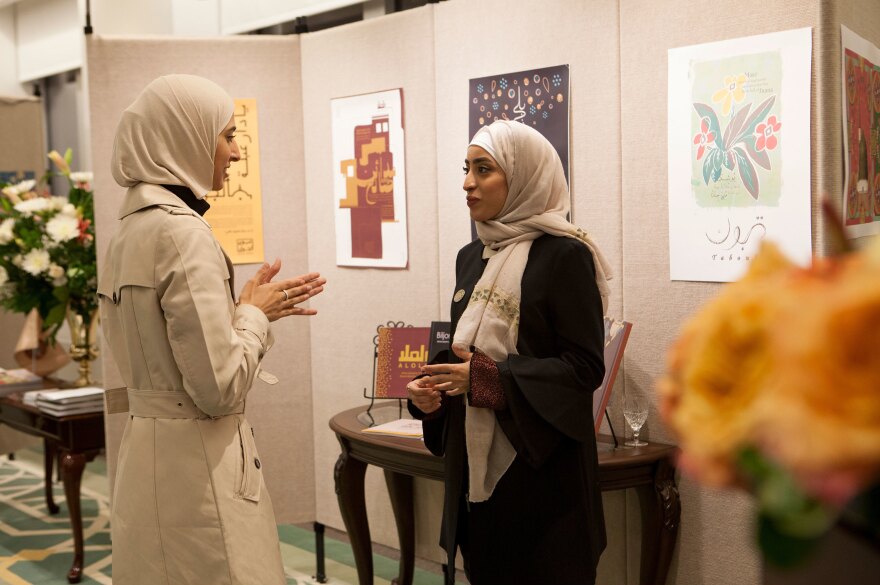 Rawabi al-Sanusi, 23, (right) speaks with another artist at the exhibition at the Saudi embassy. "I always liked to draw," she says. "I was like the weird one in my family." She designed a hardcover book paying tribute to generations past, "to show the diversity of Saudi Arabian families," she says. Her great-great-grandfather, she says, "was a king of Libya for a short time."