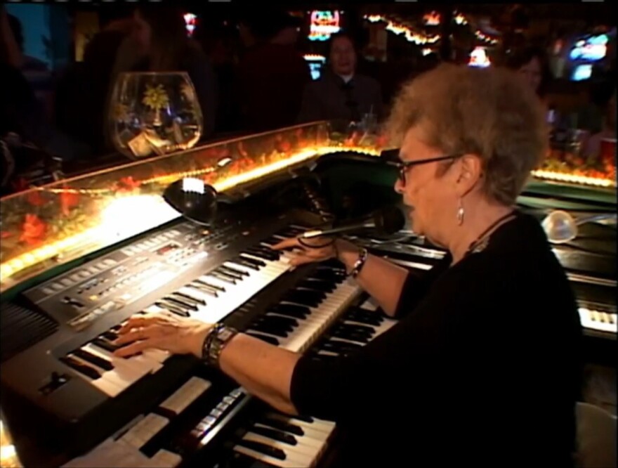 Pat Spoonheim performs on a three-tired electric piano behind a wrap around bar.