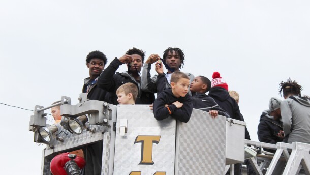 Two Manual High School basketball players show off their medals on the top of a firetruck.