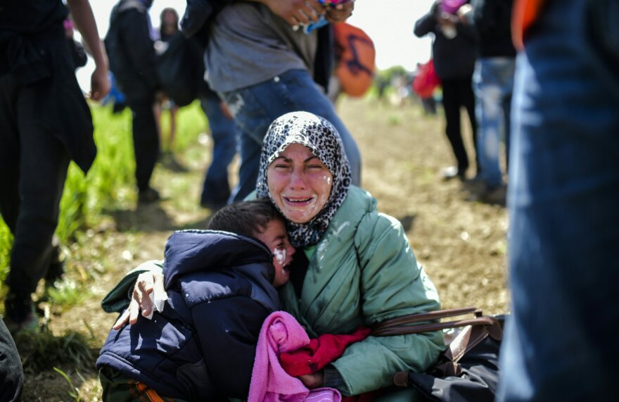 A woman and her children cry after being affected by tear gas near Idomeni on Sunday. Hundreds of people were hurt when police fired tear gas on a group of migrants as they tried to break through a fence on the Greece-Macedonia border, Doctors Without Borders said.
