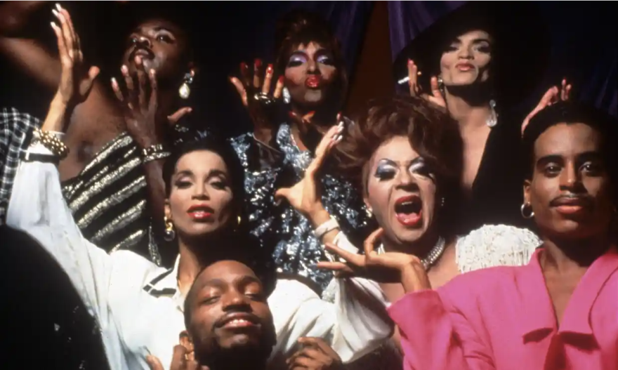 A group of LGBTQ folks smiling with their arms up