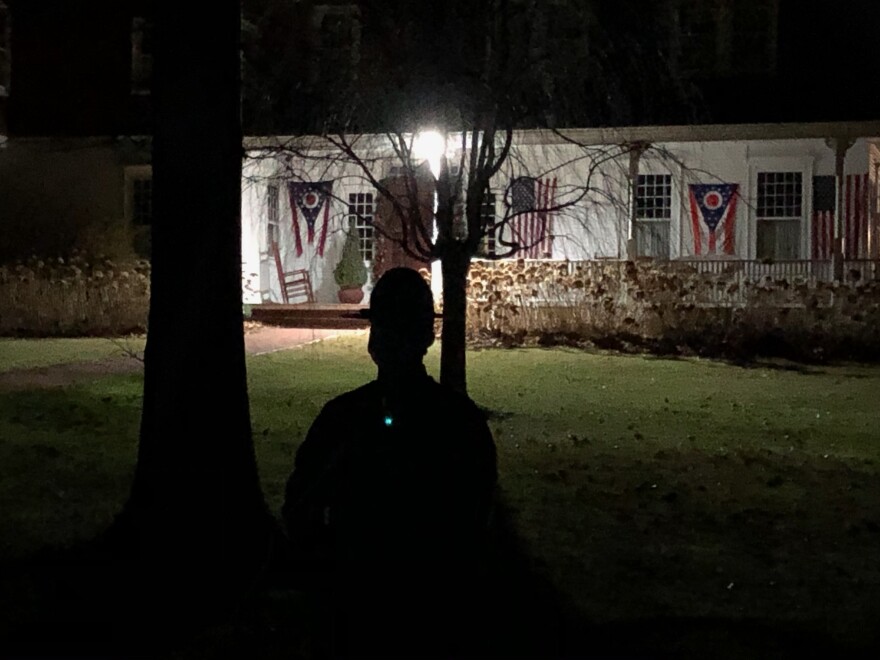 A state trooper stands in the dark in Gov. DeWine's yard 