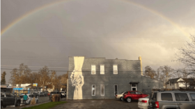 A building in the rain with a picture of two hands clasping painted on its side.