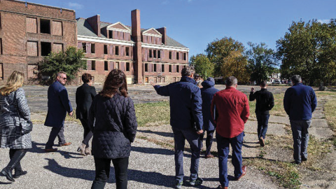 People walking in front of a shuttered and dilapidated school building in Peoria