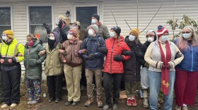 People link arms in front of a house
