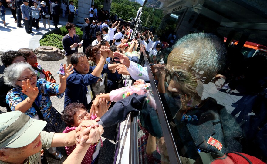 North Koreans on a bus hold hands of their South Korean relatives to bid farewell after the separated family reunion meeting at the Mount Kumgang resort on Aug. 26, 2018, in Mount Kumgang, North Korea.