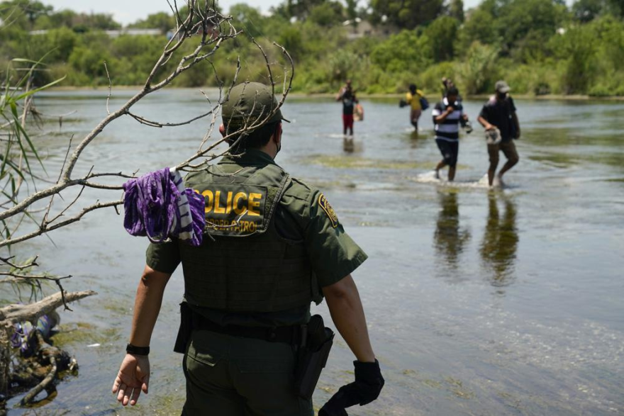 A Border Patrol agent watches as a group of migrants walk across the Rio Grande on their way to turn themselves in upon crossing the U.S.-Mexico border in Del Rio, Texas, on June 15, 2021.