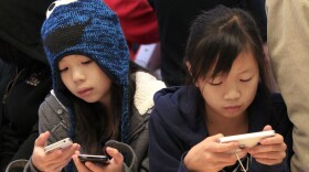 Two girls look at the Apple iPhone 4S on display at an Apple Store in San Francisco, Friday, Nov. 25, 2011. (AP Photo/Jeff Chiu)