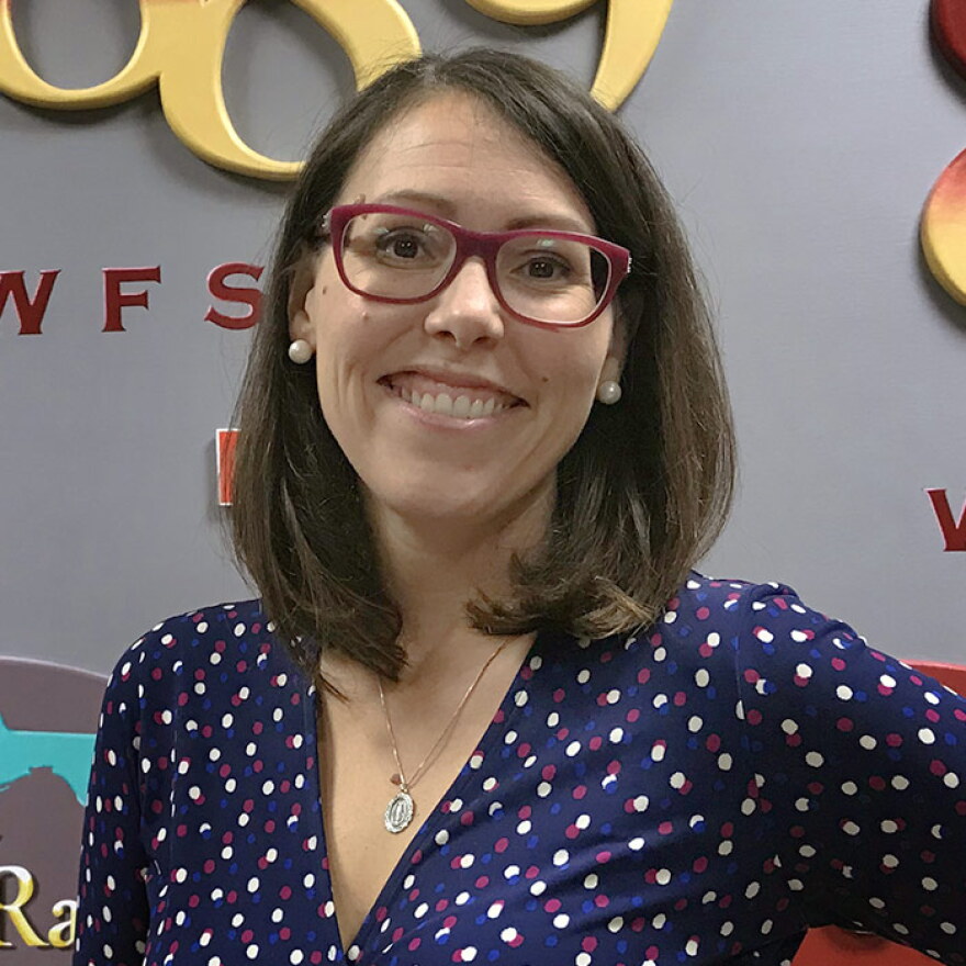 dark-haired woman in glasses and blue dress