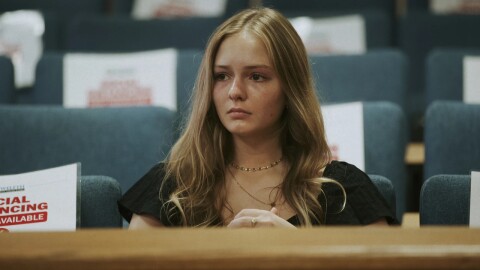 woman with blond hair with sad look almost near tears in area of public seating 