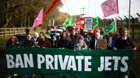 Swedish environmental activist Greta Thunberg walks alongside activist Christofer 'Chris' Kebbon (C) as they take part in a demonstration by the Extinction Rebellion (XR) climate change group, as they protest against plans to increase private jet flights, at Farnborough Airport in Farnborough.