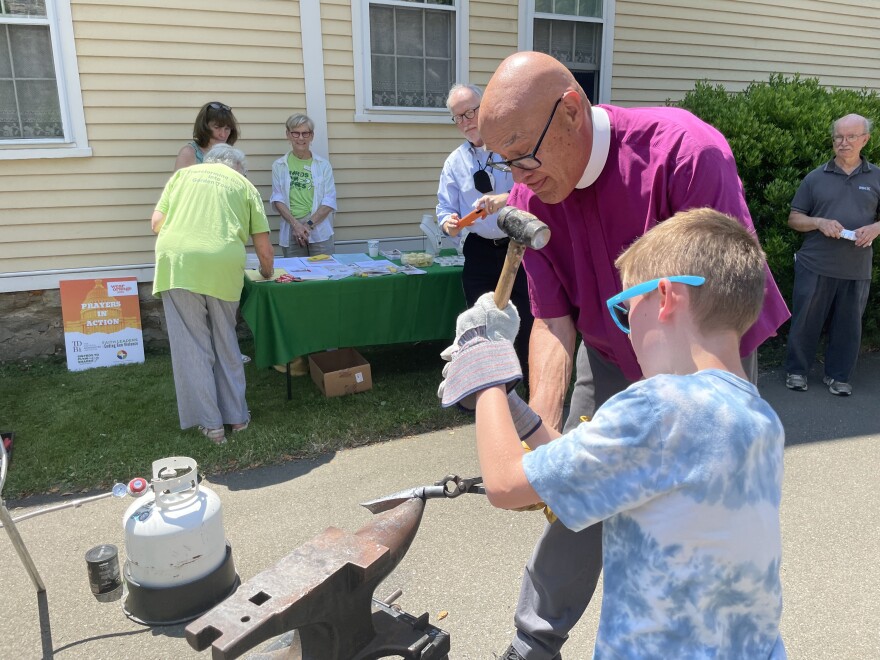  Bishop Jim Curry helps Oliver Whaley, 9, turn a shotgun barrel into a trowel outside Christ Episcopal Church in Guilford, Connecticut.