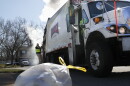 In this file photo, a sanitation worker rides the back of a truck as he works a residential route in Ohio.