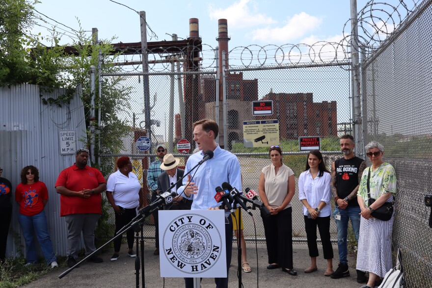 Mayor Justin Elicker stands in front of the decommissioned power plant.