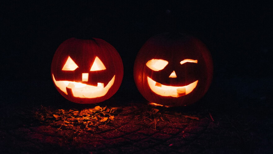 Photo of two lit up, smiling Jack-O-Lanterns side by side