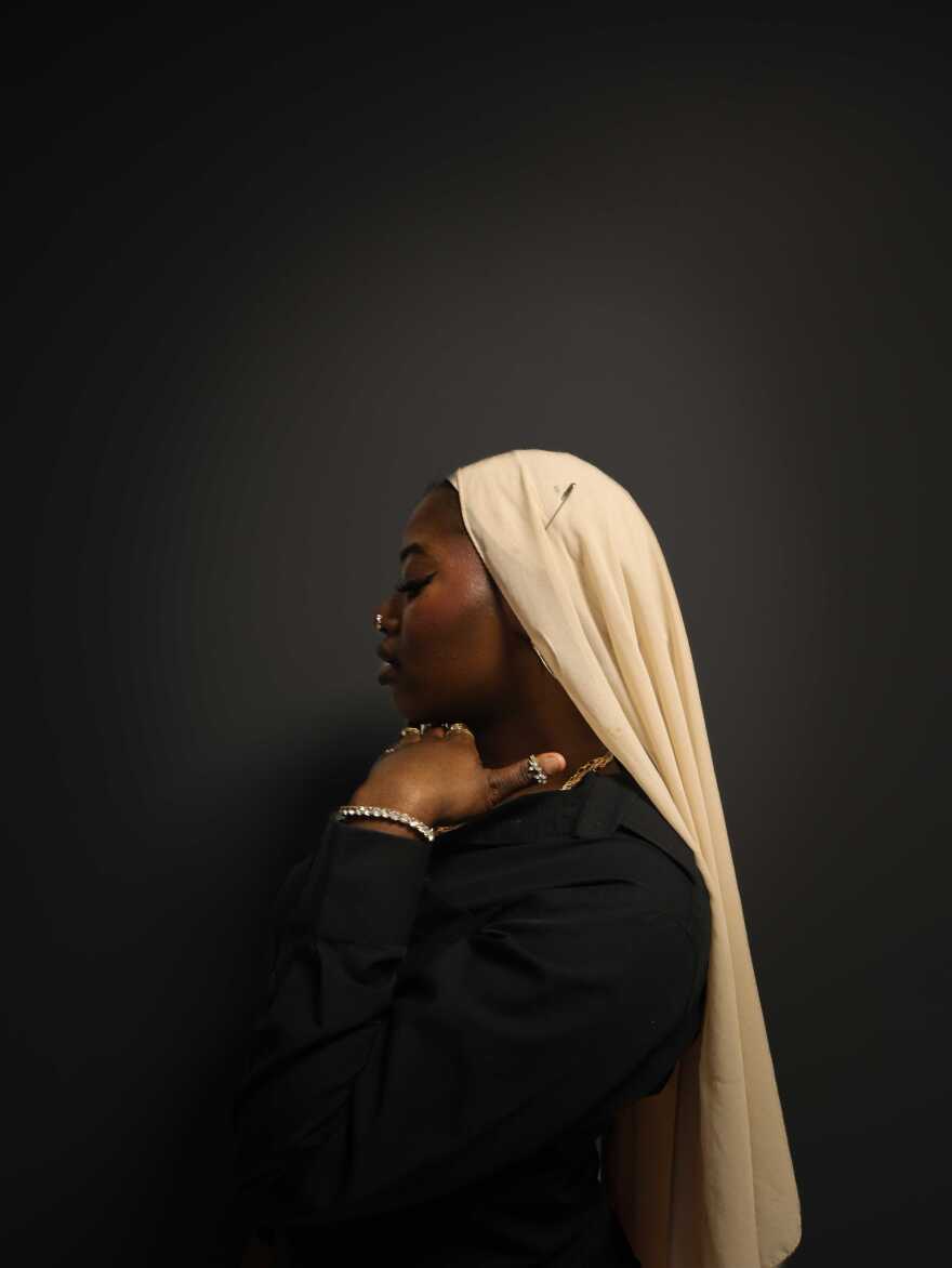 A women wearing a white scarf over her head while posing. 