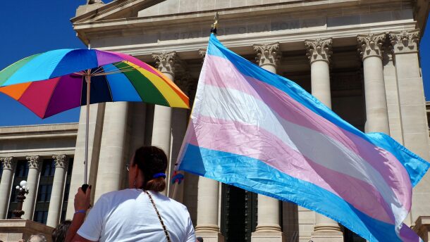 A person holds a transgender pride flag and a rainbow umbrella during a rally outside the Oklahoma State Capitol in Oklahoma City on March 14, 2024.