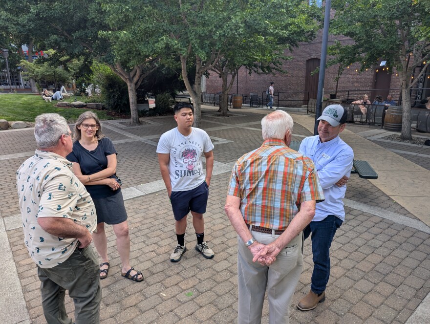 Five people stand on a brick area flanked by green trees in downtown Lewiston.