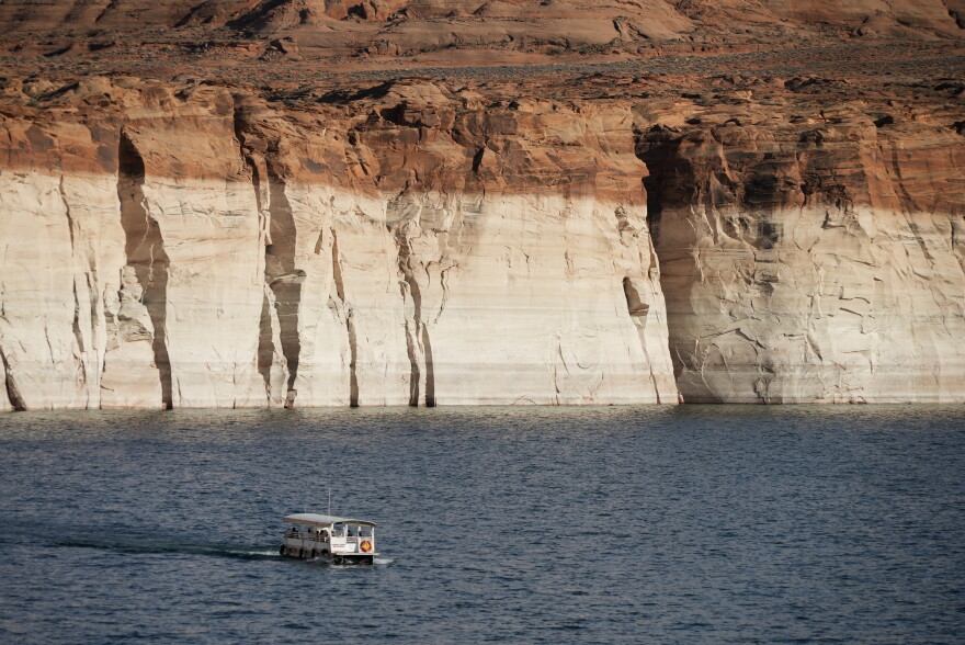 A boat floats past bathtub rings showing how low Colorado River levels have dropped Tuesday, June 7, 2022, in Page, Ariz.