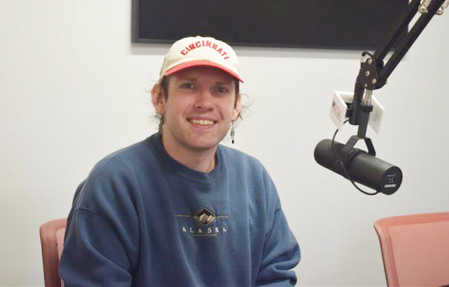 A person poses for a photo in a radio studio
