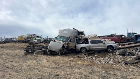 Multiple cars and a tractor trailer are smashed on the side of a highway.