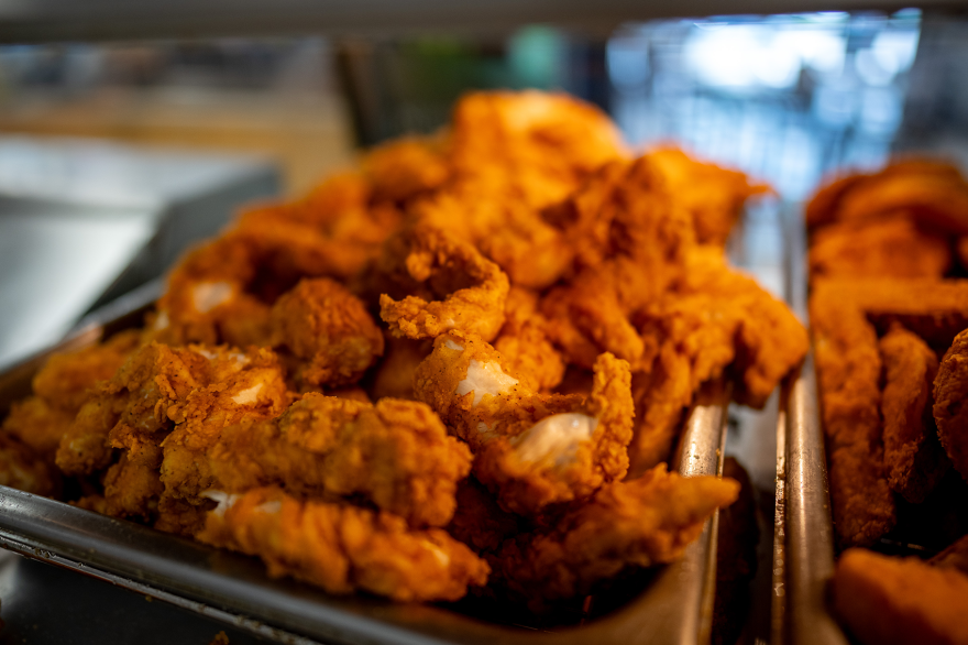 A pile of chicken strips in a metal basket. 