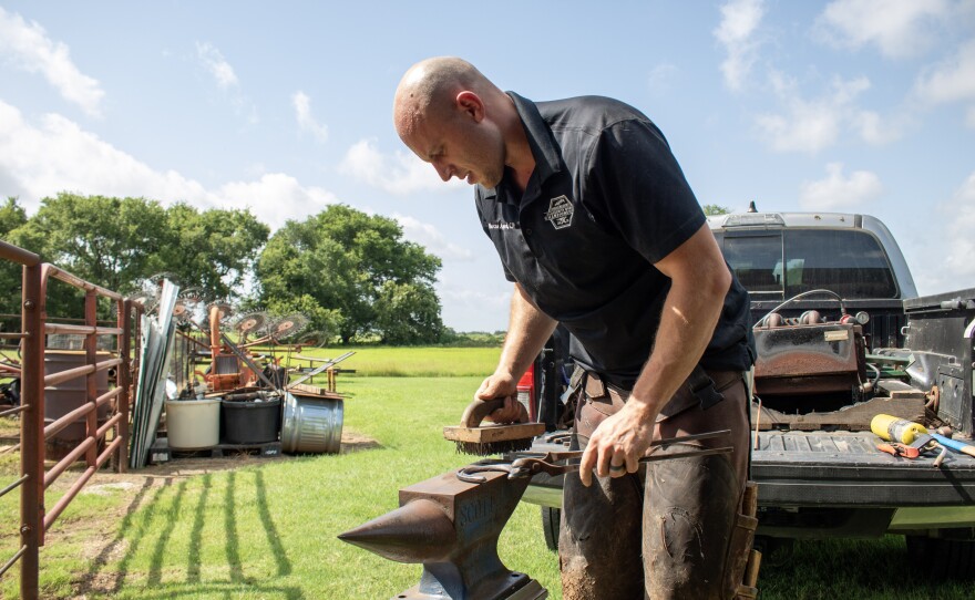 Waco farrier Marcus Appleyard cleans a horse shoe on his anvil before fitting it to the horse.