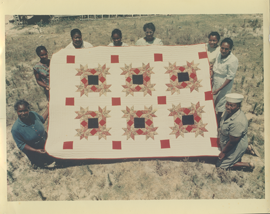 Women from the Freedom Quilting Bee displaying a quilt