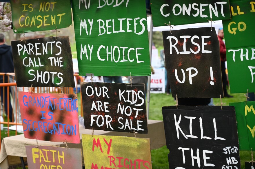 Signs at the state capitol where protesters gathered to speak against a bill that would remove the religious exemption from childhood vaccination requirements on April 27, 2021. 

