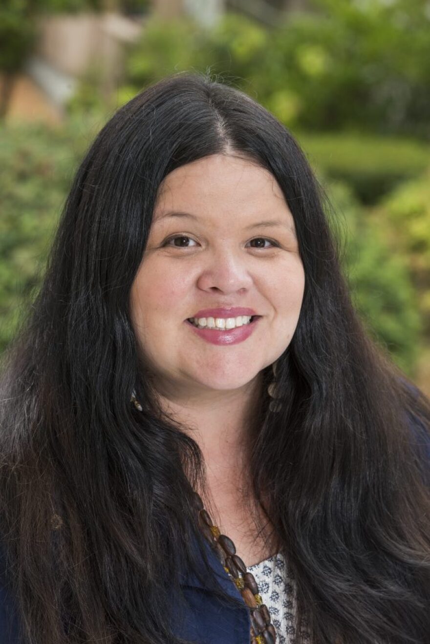 A headshot of a woman with long, dark hair