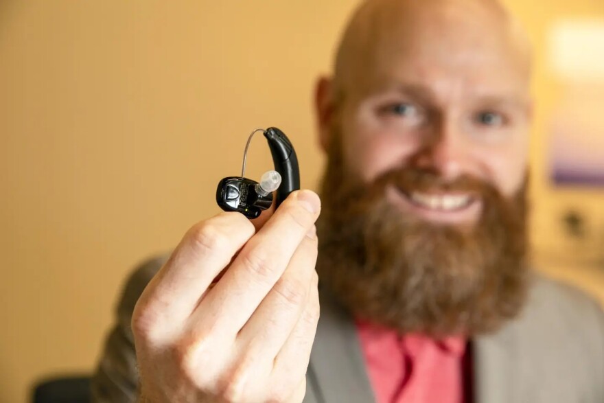 A man displays a hearing aid. Beltone is accepting nominations for free devices through its holiday giveaway program.