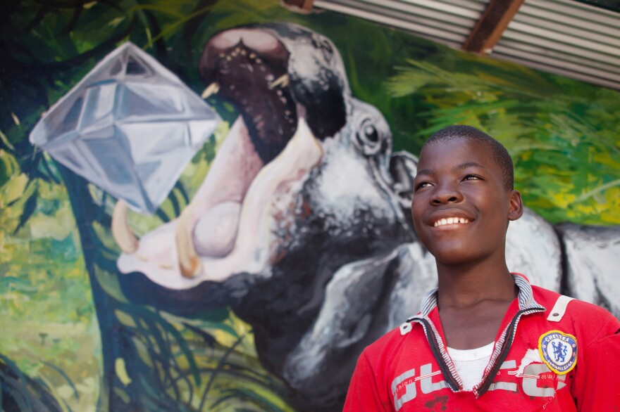 Abel Dassin, 14, had a hand in painting the hippo's skin. (The diamond in its mouth is part of local folklore — if you find a hippo and don't kill it, the animal will give you a gem.)