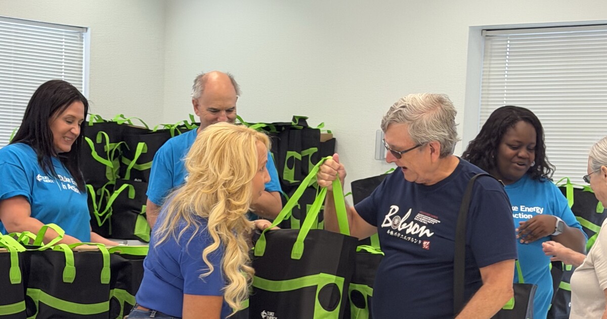 A female Duke Energy employee hands a senior a green bag