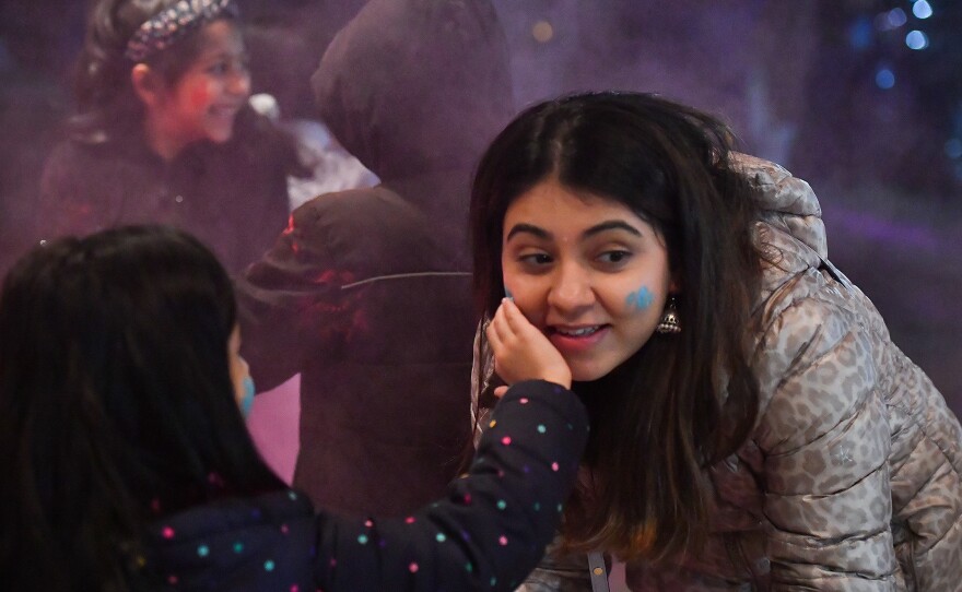 6-year-old Dhwani Patel puts colors on her friend, Jinal Dave, at the Holi festival.