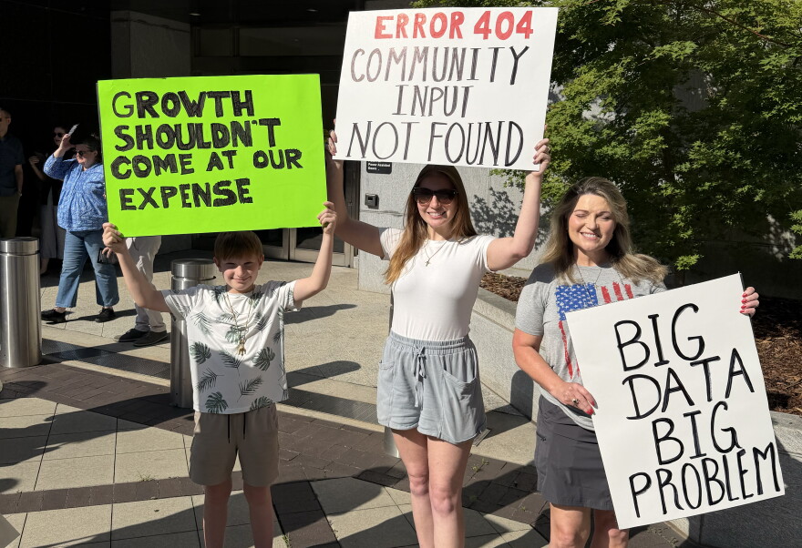 Three people hold signs. One says "Error 404: Community input not found."