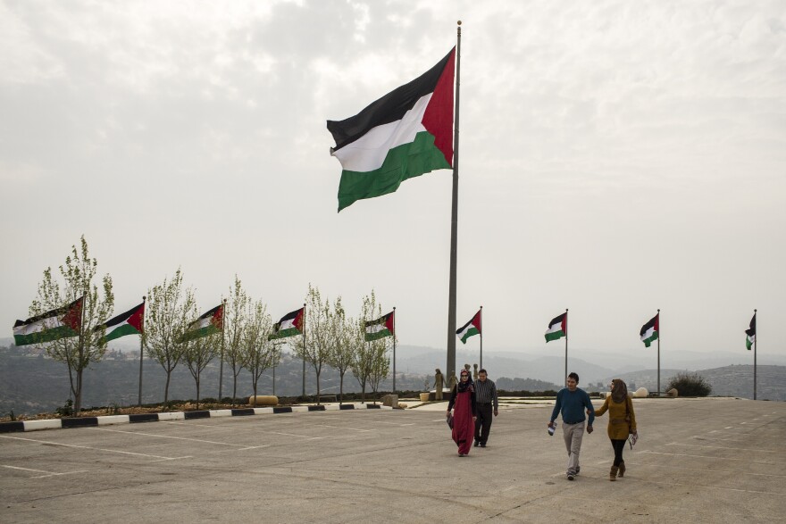 Palestinians exit the Rawabi showroom after viewing the development. On the ridge behind the Palestinian flag is the Israeli settlement of Ateret. The flag, billed as the biggest Palestinian banner, has been stolen three times, Rawabi employees say -- and they blame Israeli settlers.