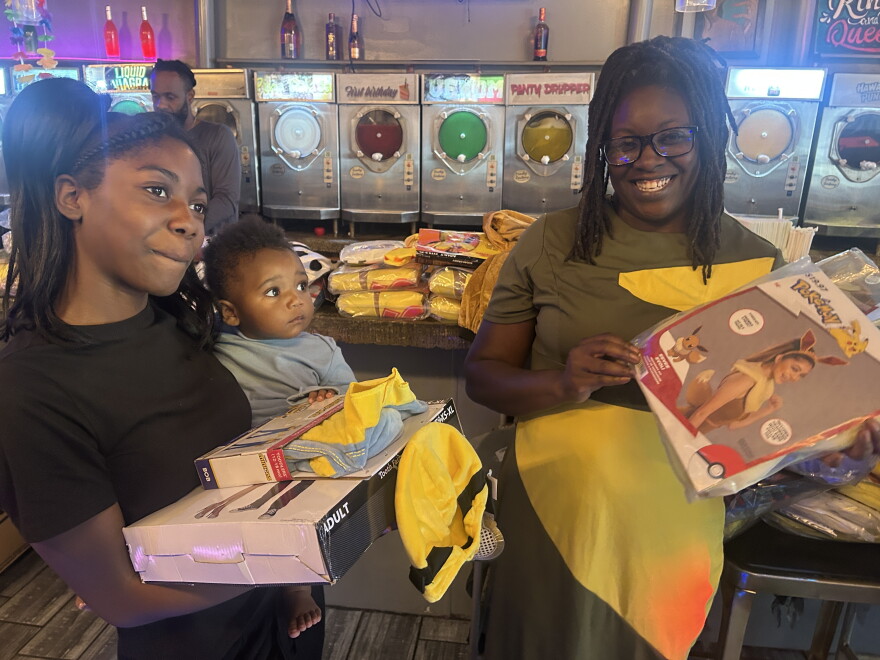 Mother Tomeka Hawkins-Woodcox , her infant daughter XX, and her teenage daughter with the costumes they've selected.