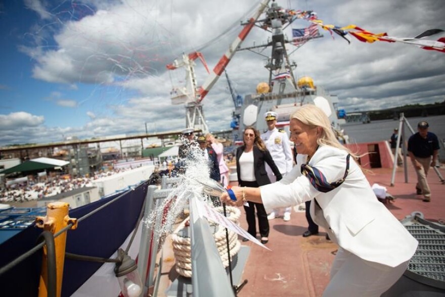 Ryan Manion, sponsor, breaks the christening bottle on the bow of the future USS John Basilone (DDG 122). Manion is the president of the Travis Manion Foundation, named for her brother who was killed in action in Iraq.