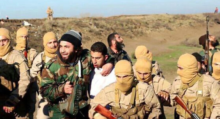 Islamic State militants captured Moath al-Kasasbeh on Dec. 24 after his warplane went down in Syria. This image posted by the Raqqa Media Center shows militants with al-Kasasbeh, wearing the white shirt, in Raqqa, Syria.