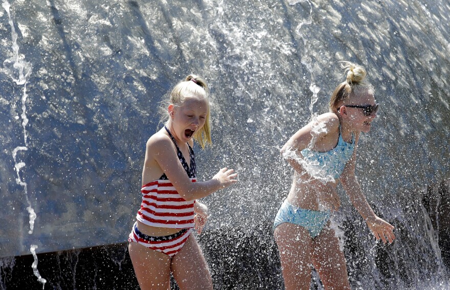 Two girls play in warm and sunny weather at the International Fountain in Seattle on Friday, July 13, 2018. 