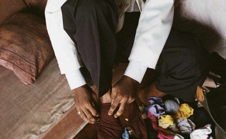 A <em>sapeur</em> named Allureux decides to put on his maroon socks because they match with his elbow tie. The rule of the three colors — one should not match more than three colors at a time — is one of the principles of the <em>Societe des Ambianceurs et des Personnes Elegantes</em>.